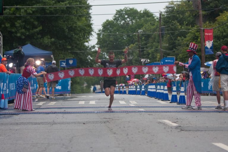 A runner crossing a finish line during a race, celebrating progress after completing their first running event.