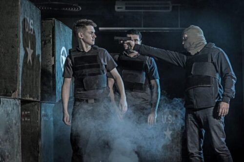 Krav Maga training scenario involving a practitioner facing a gun threat during a high-pressure close-quarters drill.