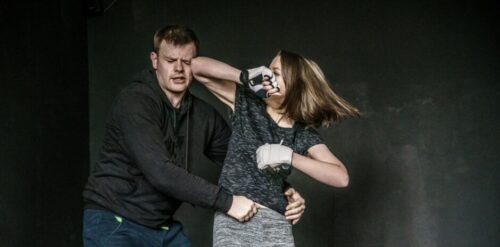 Woman defending herself during a realistic street confrontation scenario in an urban environment.