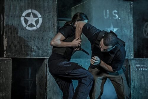 Woman practising a knife defence drill against an attacker during Krav Maga class training.