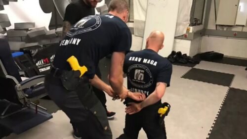 Krav Maga practitioners restraining and handcuffing an assailant during a law enforcement control training scenario.
