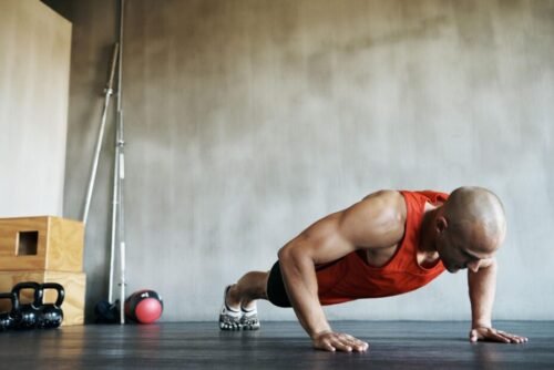 Man performing push-ups in a garage gym, demonstrating consistency, discipline, and the daily habits that reinforce a training identity.