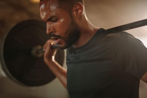 Man preparing to perform barbell back squats in a gym, representing training as self-respect, personal standards, and long-term health.