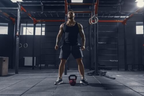Man standing over a kettlebell preparing to train, representing commitment, routine, and making training a permanent part of daily life.