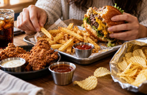Burger, fries and a soft drink on a restaurant table, illustrating a calorie-dense, highly palatable meal that is easy to overconsume.