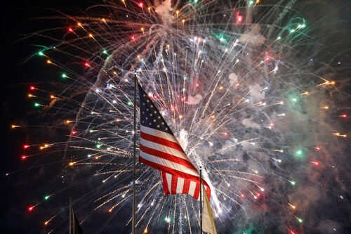 US flag with fireworks in the background, symbolizing the celebration of Independence Day and the triumphant finish of the 4th of July workout challenge.