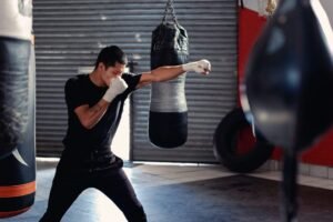 Young boxer with hand wraps shadowboxing in gym, training boxing fundamentals.
