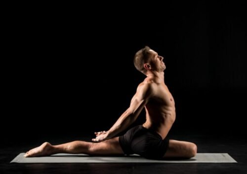 Man performing Pigeon Pose stretch, illustrating yoga’s role in restoring hip mobility, releasing tight muscles, and improving joint range of motion for athletes and lifters.
