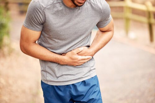Runner experiencing stomach discomfort during training, illustrating how gut issues can affect performance under physical stress.
