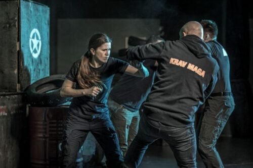 Woman training intensely in a Krav Maga class focused on striking and pressure-based drills.