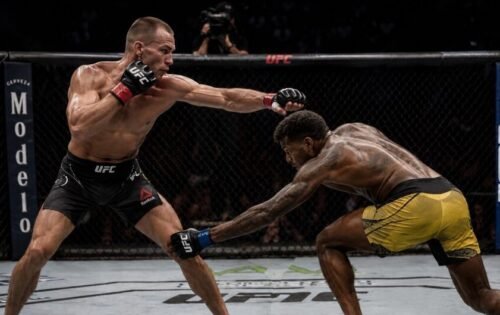 MMA fighter throws a long punch while the opponent lowers their level and reaches towards the lead leg.