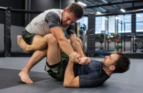 Straining MMA beginner attempts to overpower a calm grappling partner who remains balanced and composed.
