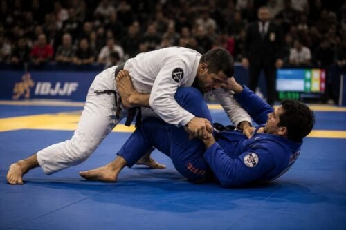 Brazilian Jiu-Jitsu competitors engage in a guard passing battle during a tournament match, demonstrating the positional strategy, control, and technical grappling that define BJJ.