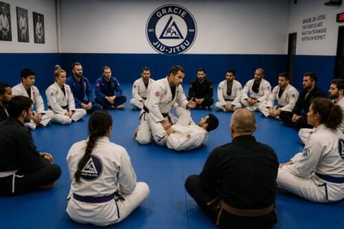 Brazilian Jiu-Jitsu instructor demonstrating a guard pass technique to a seated class of students during a structured academy lesson.