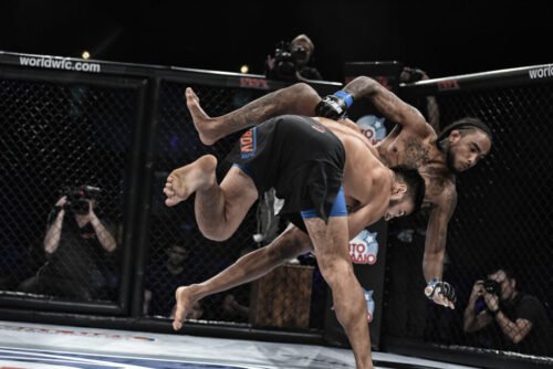 MMA fighter executing a takedown against an opponent during a cage fight.